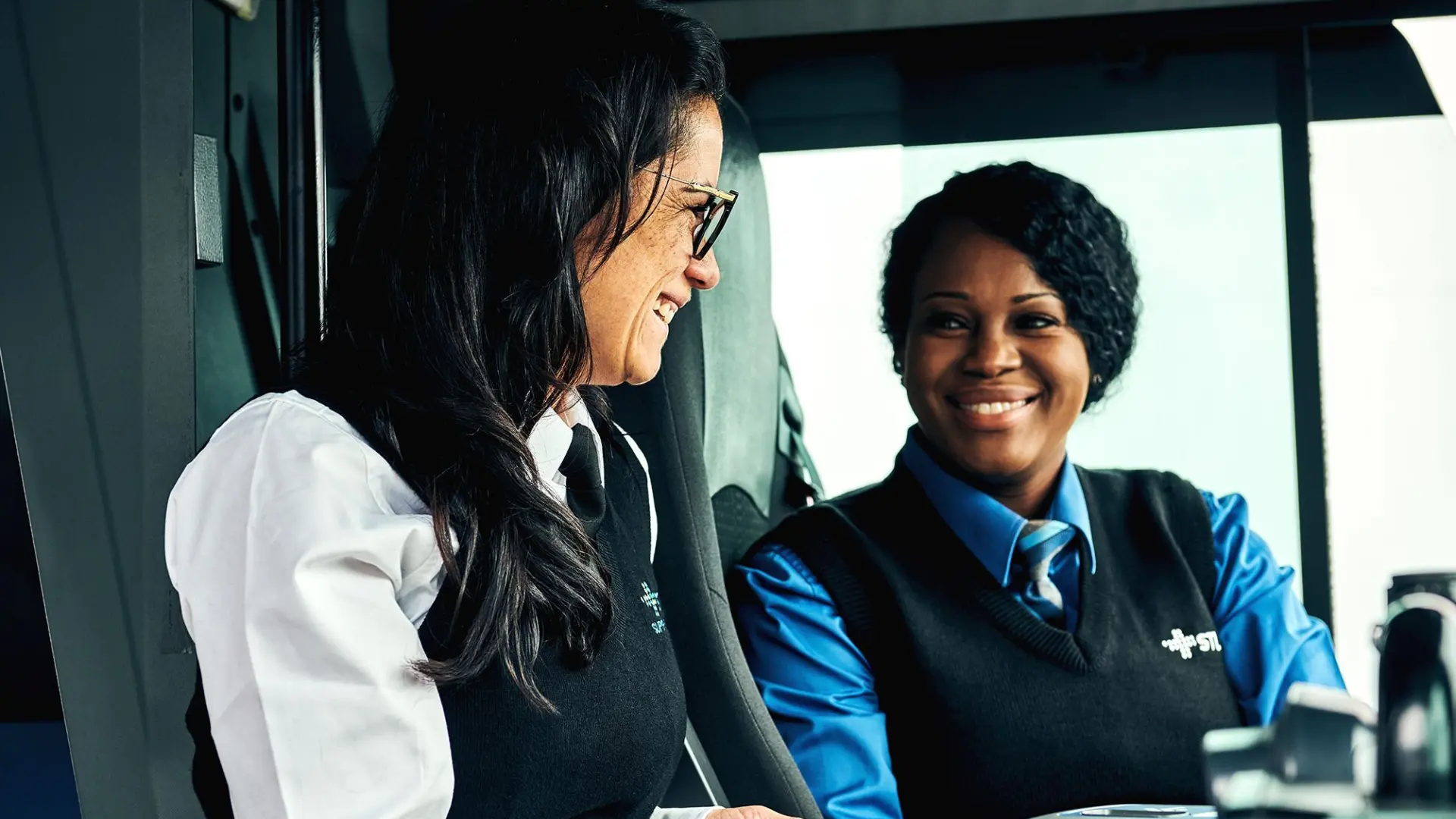 Chauffeure d'autobus et superviseure STL discutant au poste chauffeur dans l'autobus.